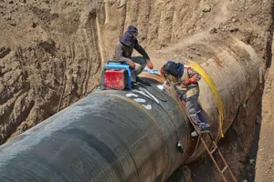 Pipeline laying equipment lowering large pipe into trench on construction spread