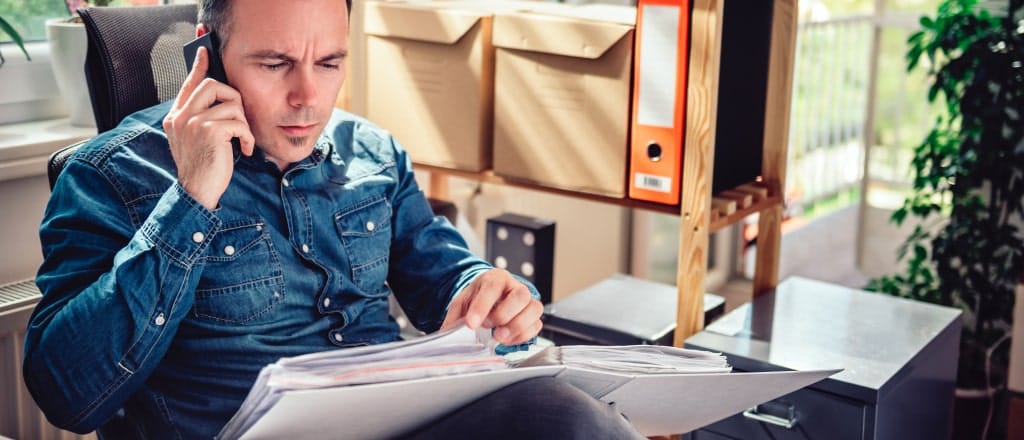 worker going through papers and talking on the phone