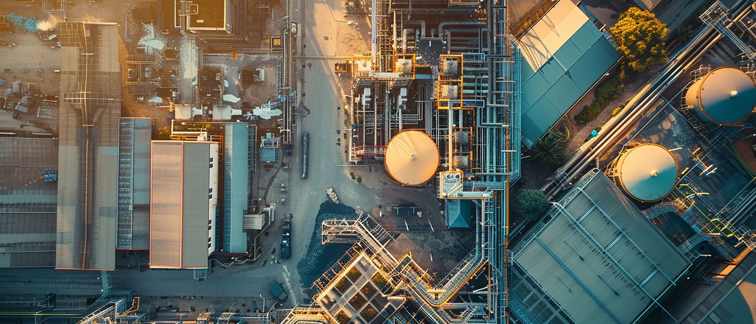 blog_your-system Aerial drone view of an oil and gas processing facility showing storage tanks, pipelines, and industrial infrastructure